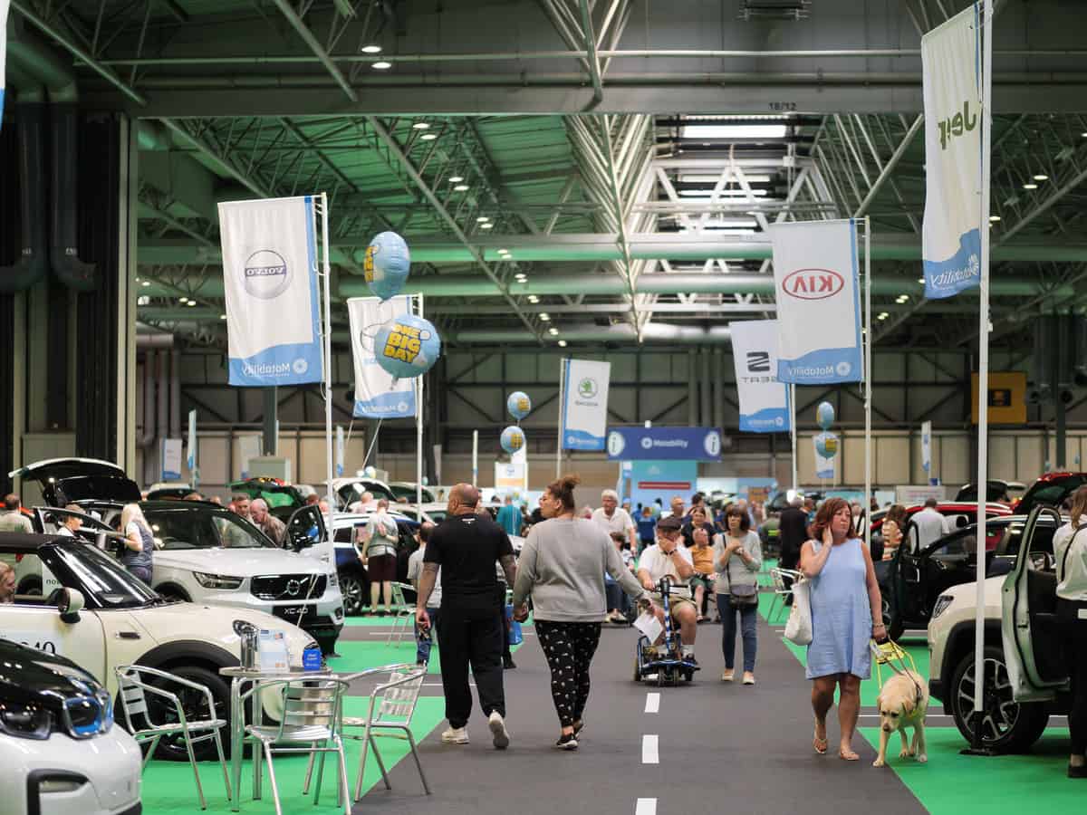 People exploring cars at an indoor car exhibition