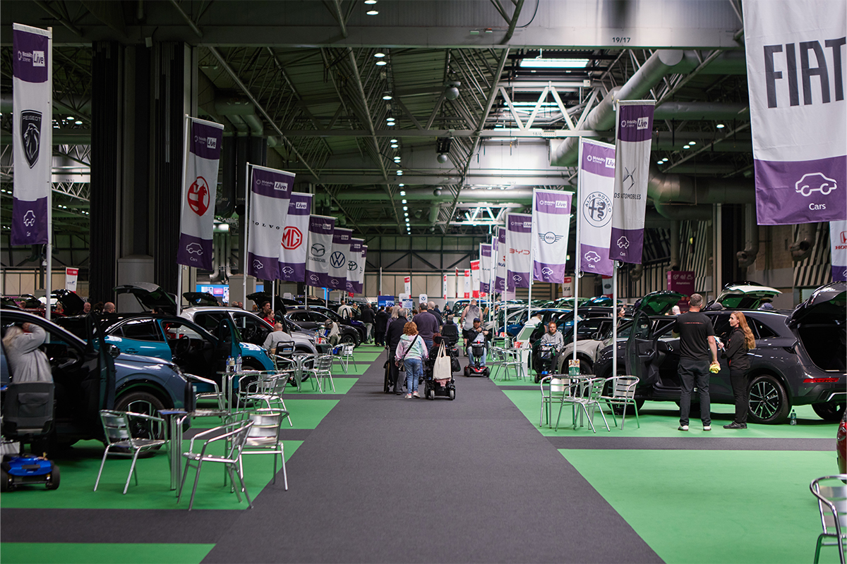 Motability Scheme Live exhibition hall with car displays, brand banners, and visitors exploring vehicles.