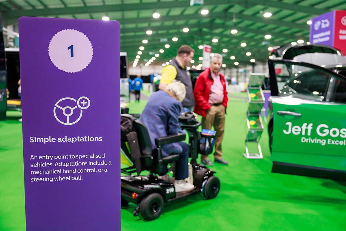 A purple information sign for simple adaptations next to a mobility scooter