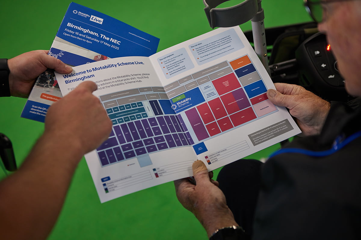 A close-up of a person holding an open event guide showing a colourful floor plan map